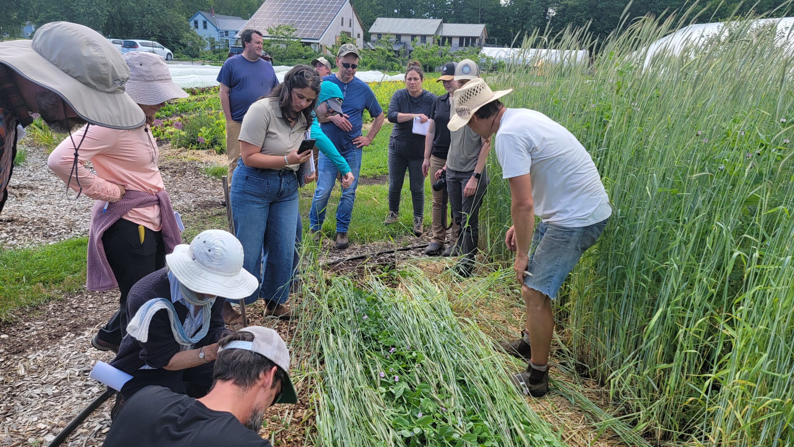 Kevin Allison shows tools to workshop visitors in garden